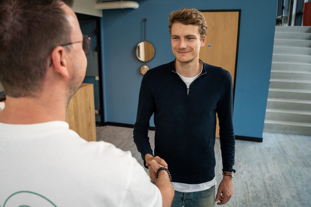 Een collega van REUS verwelkomt een klant op kantoor