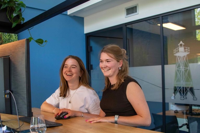 Creatieve marketeer bij REUS: twee collega's lachen samen achter de computer