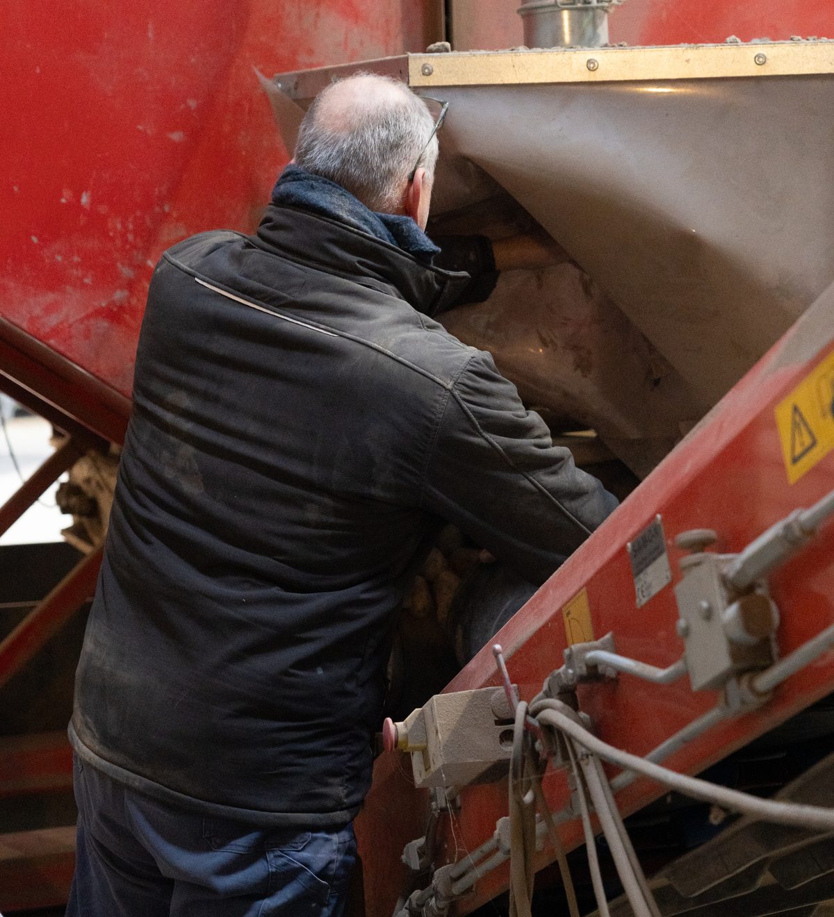 Medewerker van Agrico aan het werk bij een machine in de bewaarschuur