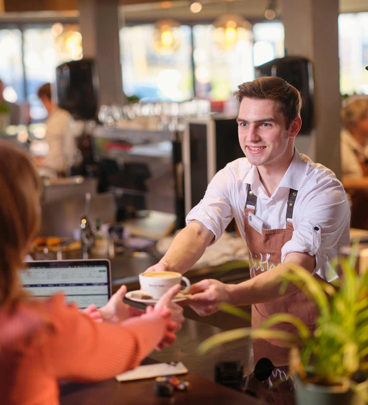 Een gastheer van Jitha’s Deli serveert koffie aan een gast